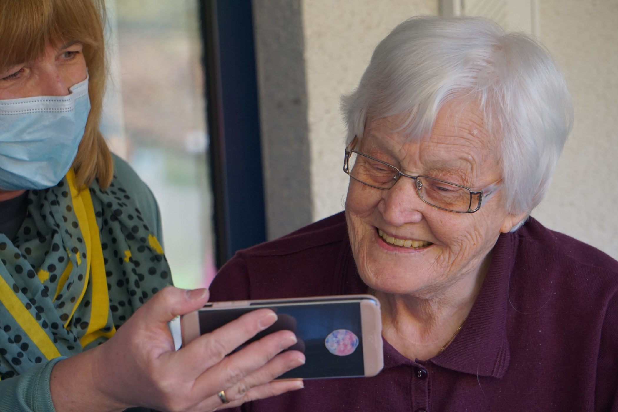 A carer helping an older lady to use an iPhone