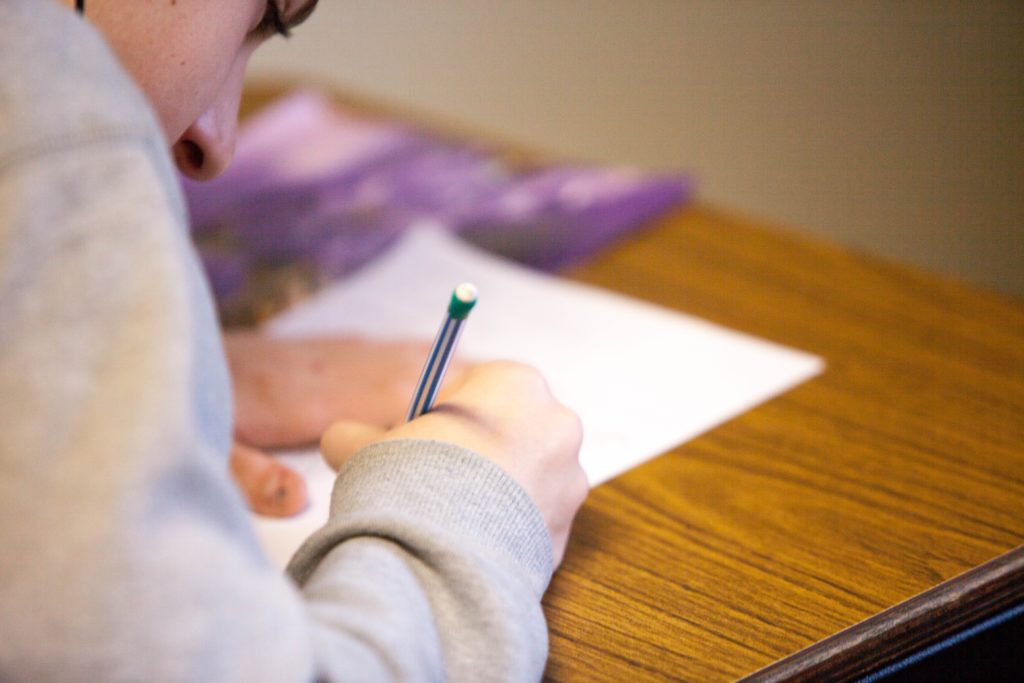 image of a young person at a desk writing on paper