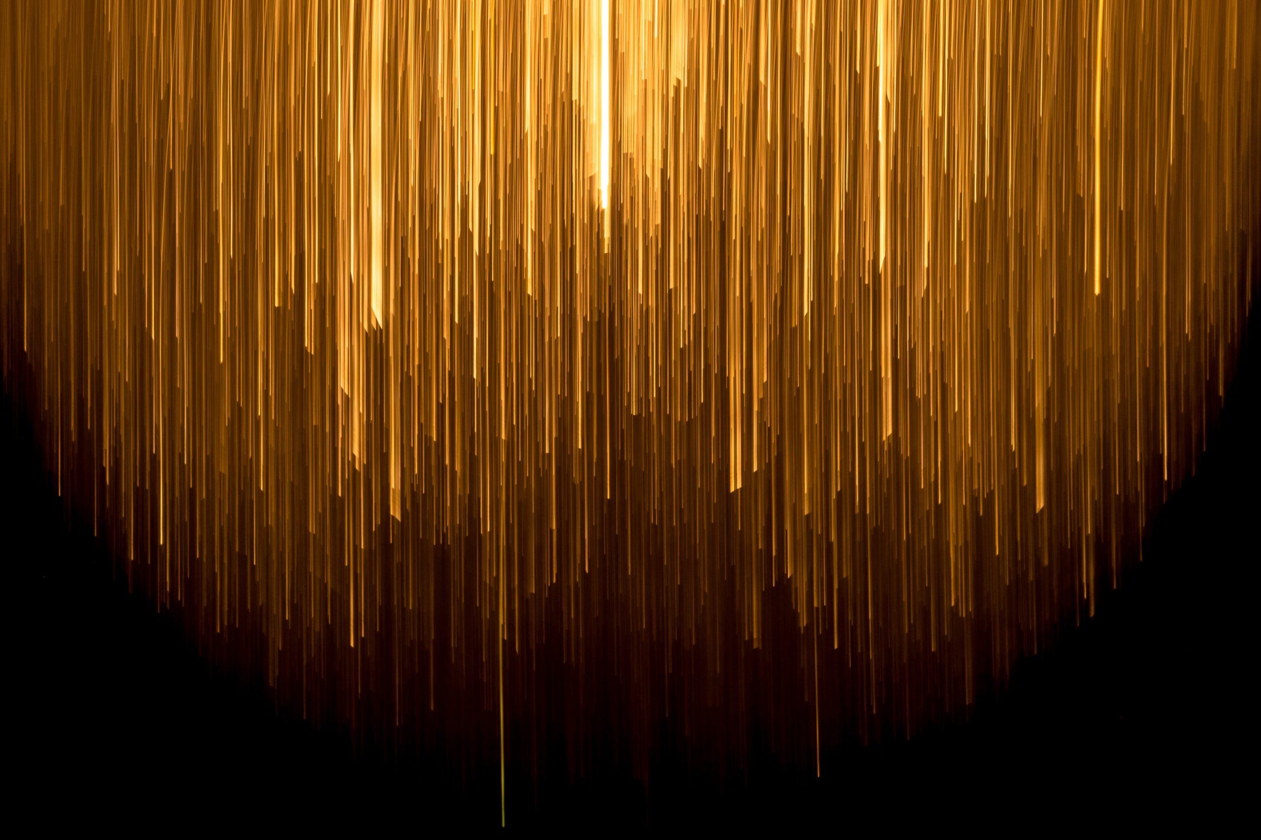 an abstract image - gold lines shooting down on a black background