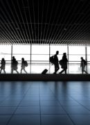 Silhouettes of people walking through an airport