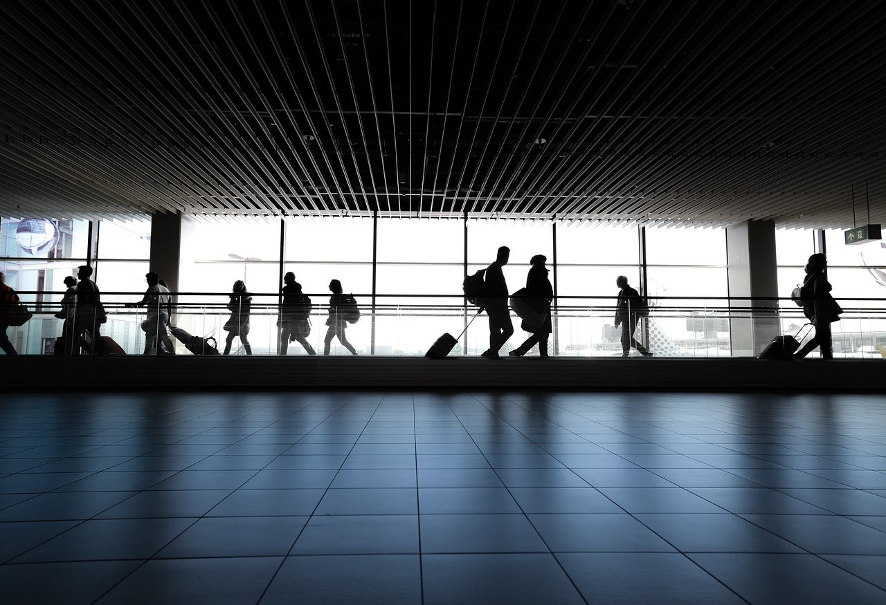Silhouettes of people walking through an airport