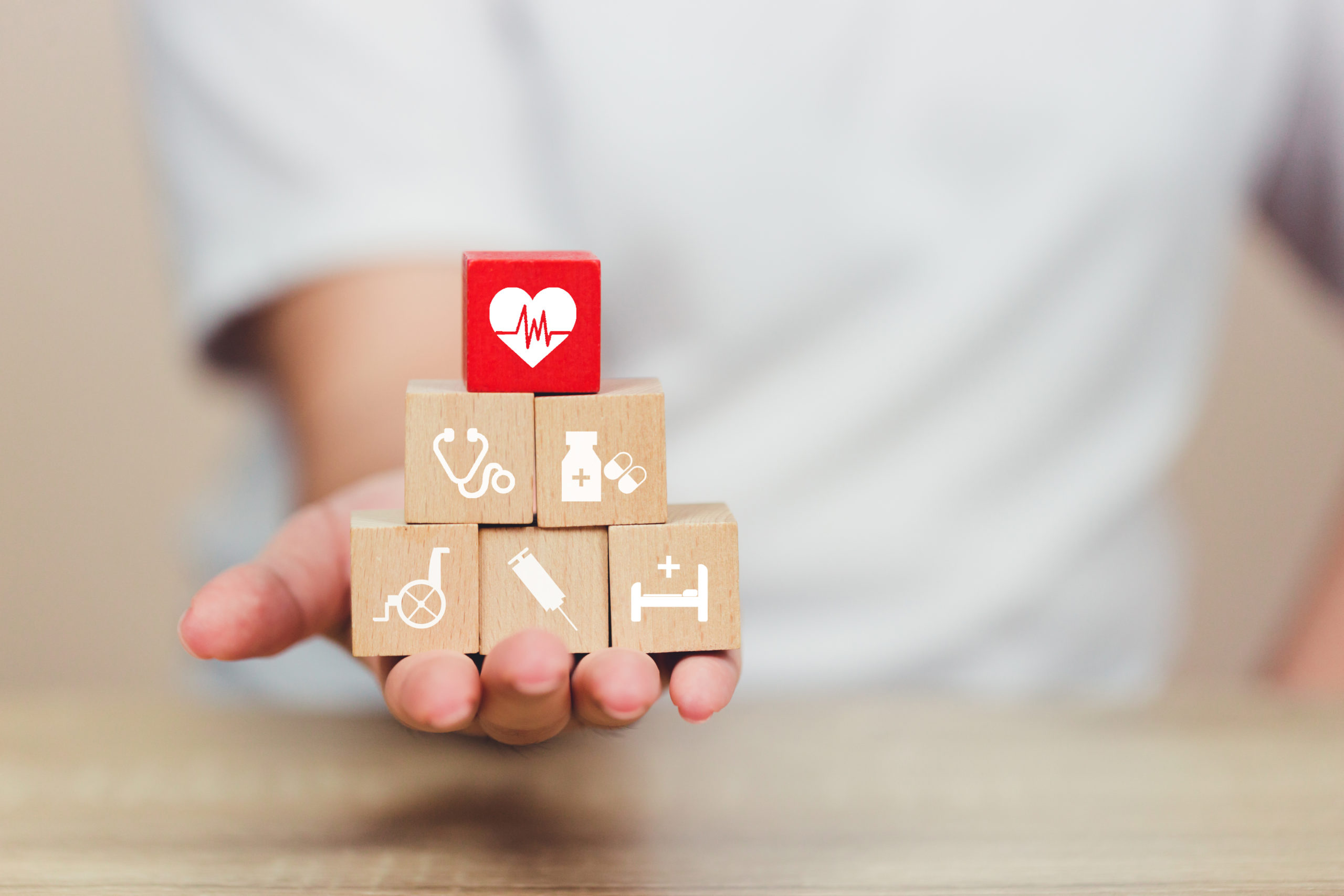 hand arranging wood blocks with icons for healthcare medical