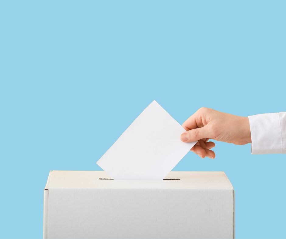 a hand dropping a poll card into a voting box