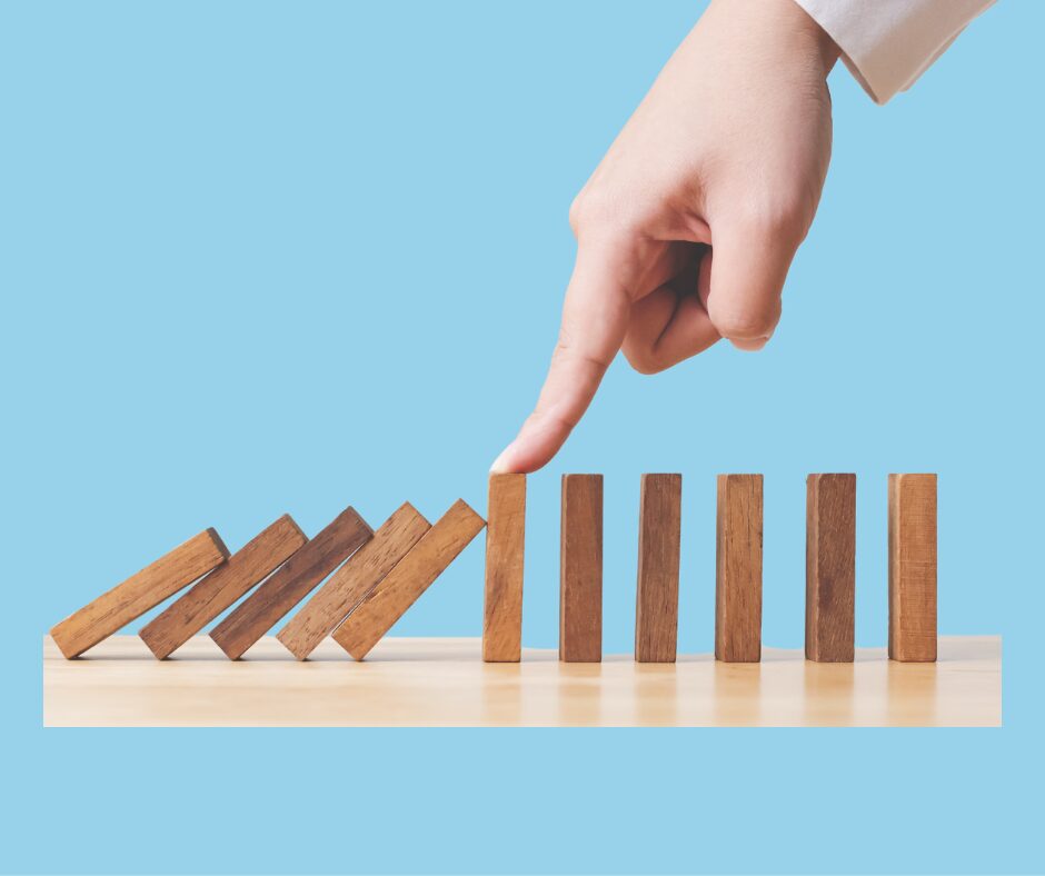 a line of dominos, a finger stopping them from toppling over half way down the line