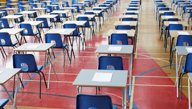 Exam hall with blue chairs and wooden desks