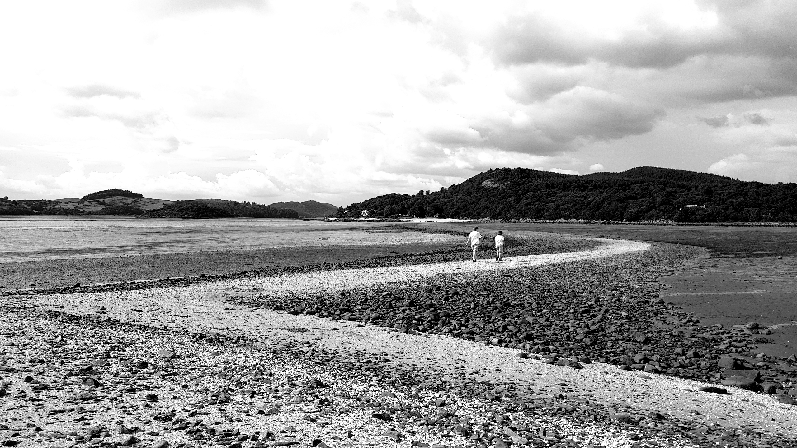 A black and white picture of a beach with only two people on it