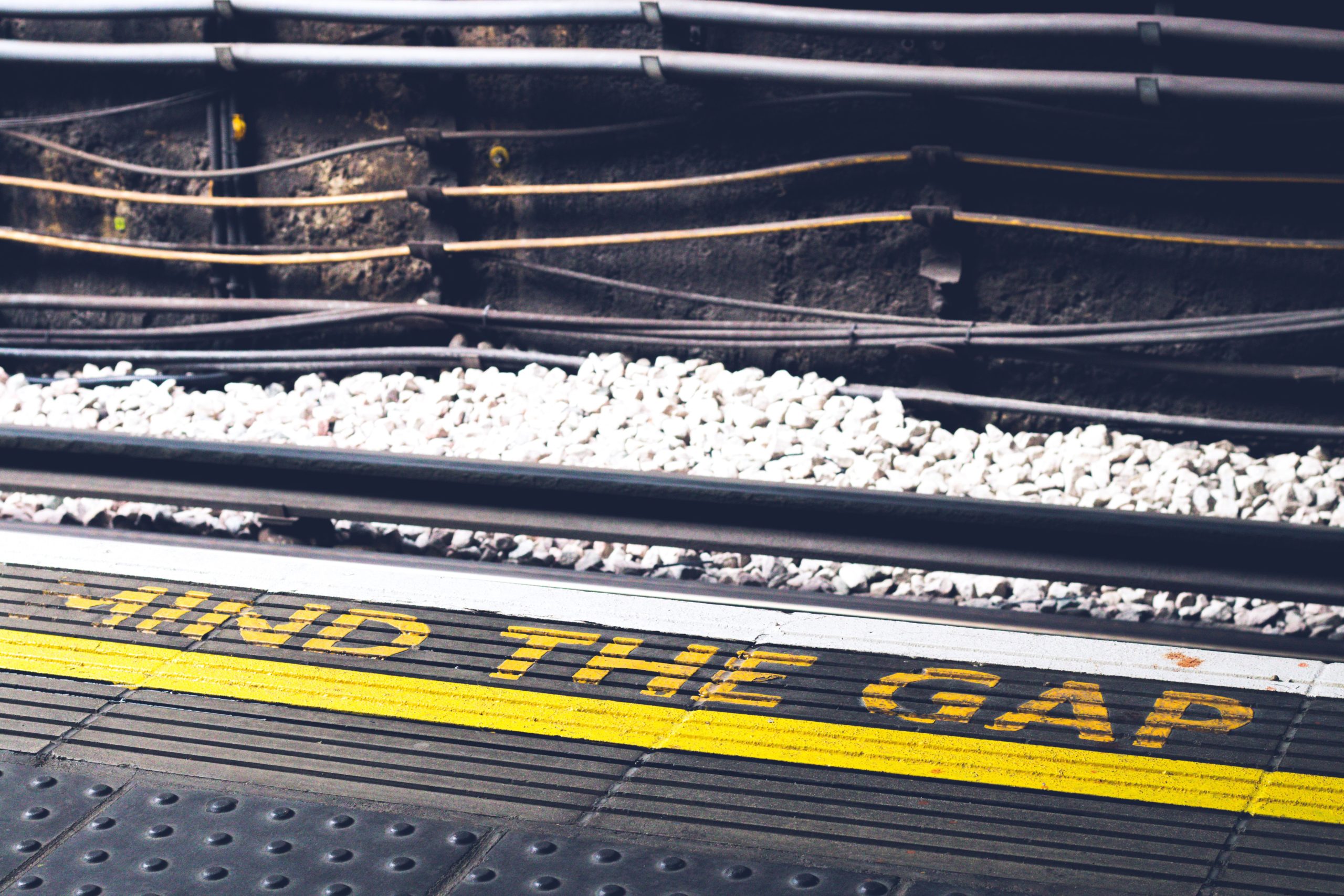 A train station platform that has Mind The Gap written on it in yellow paint