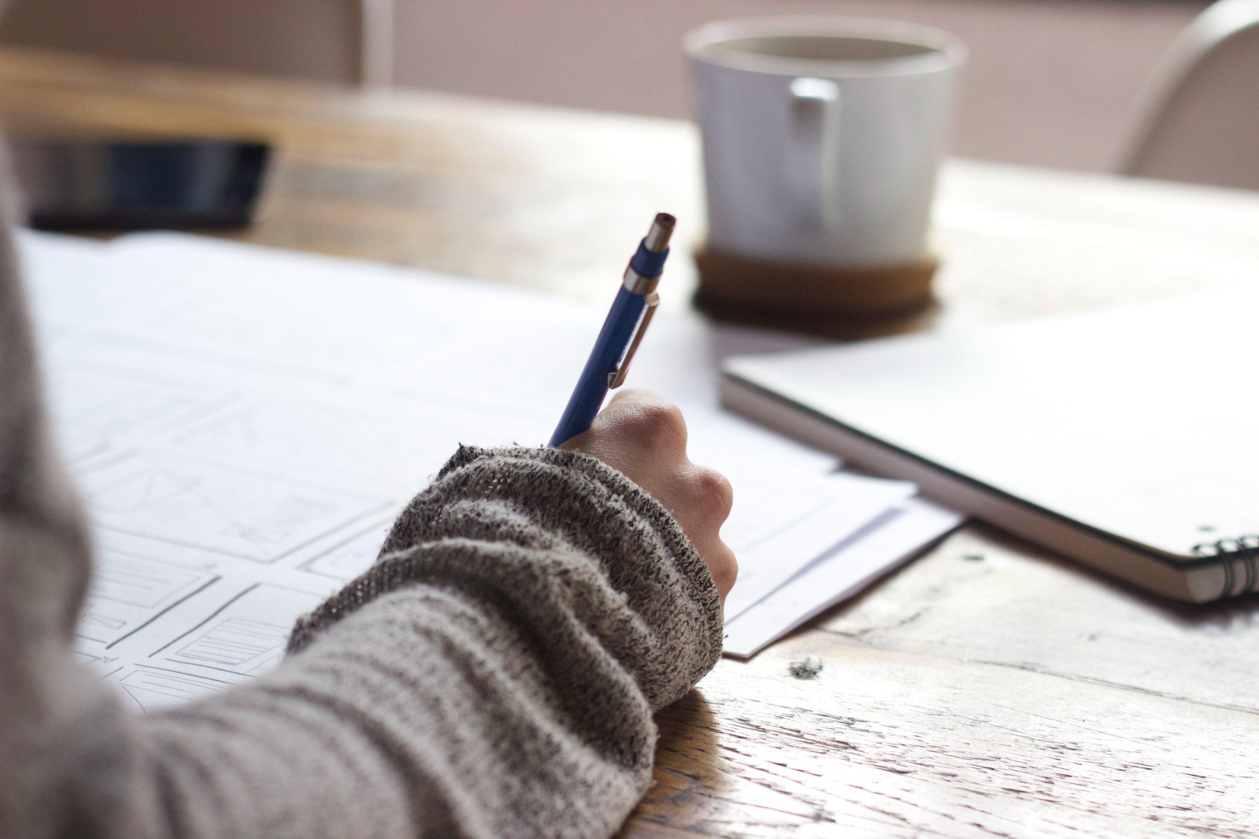 A person writing a document on a table working from home