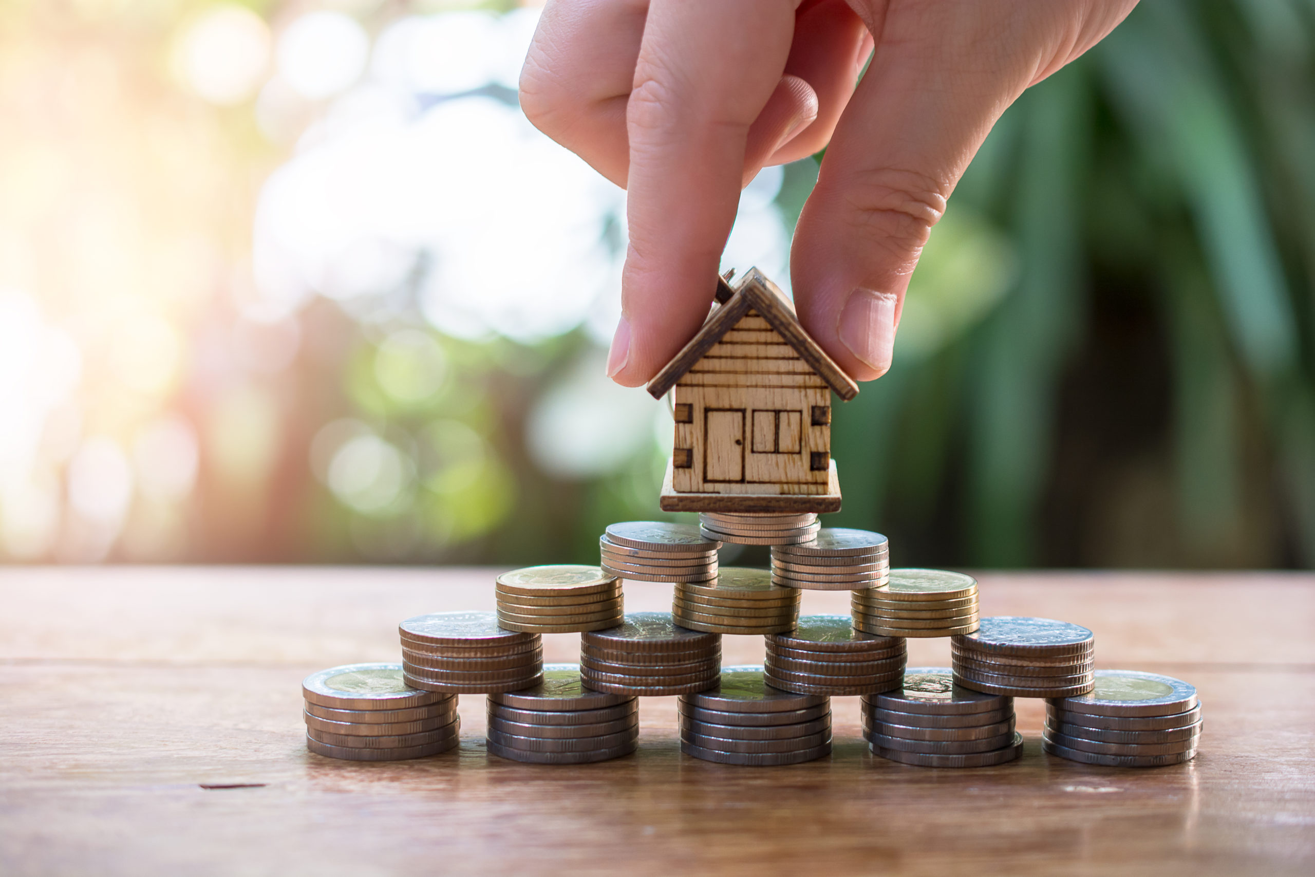 putting house model on money coins saving for concept investment
