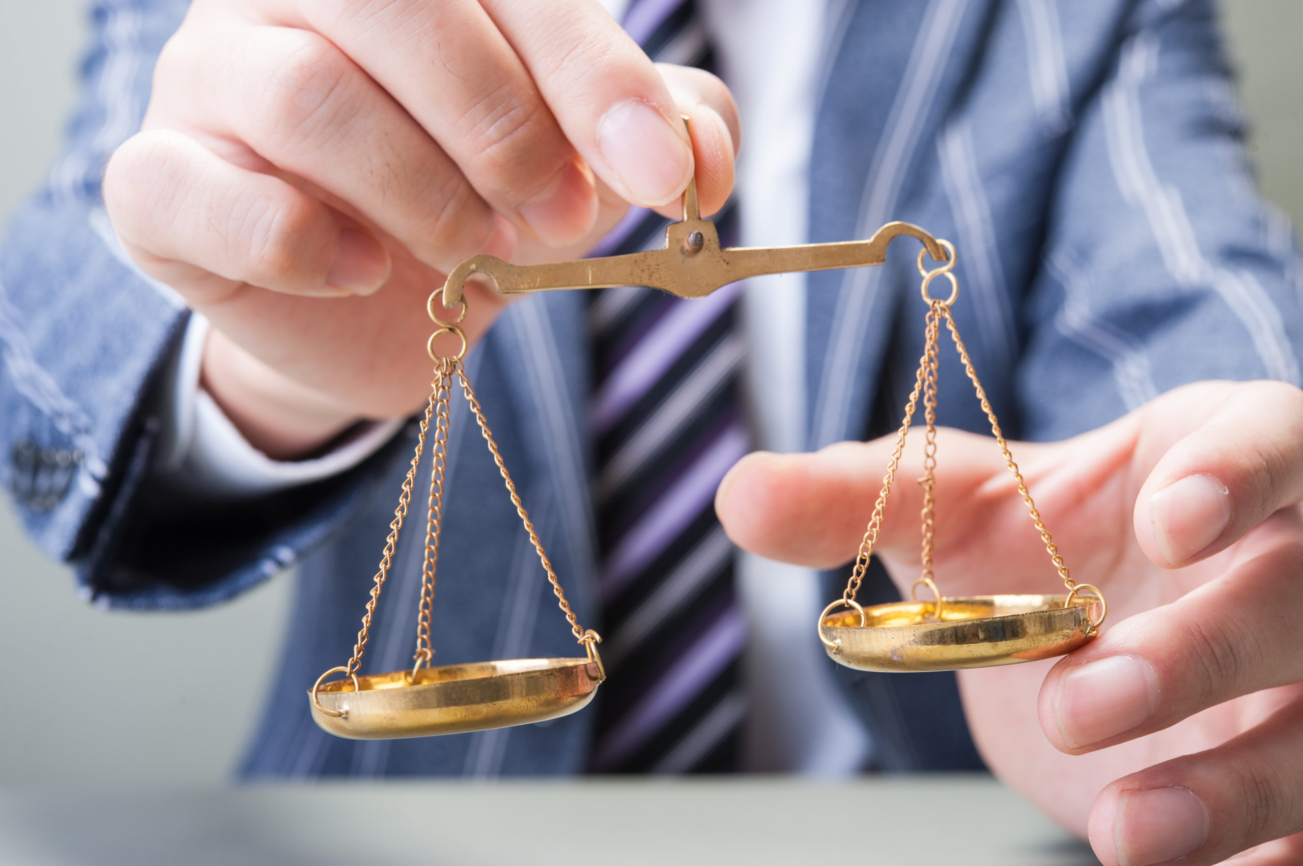 A hand holding a miniature set of balancing scales