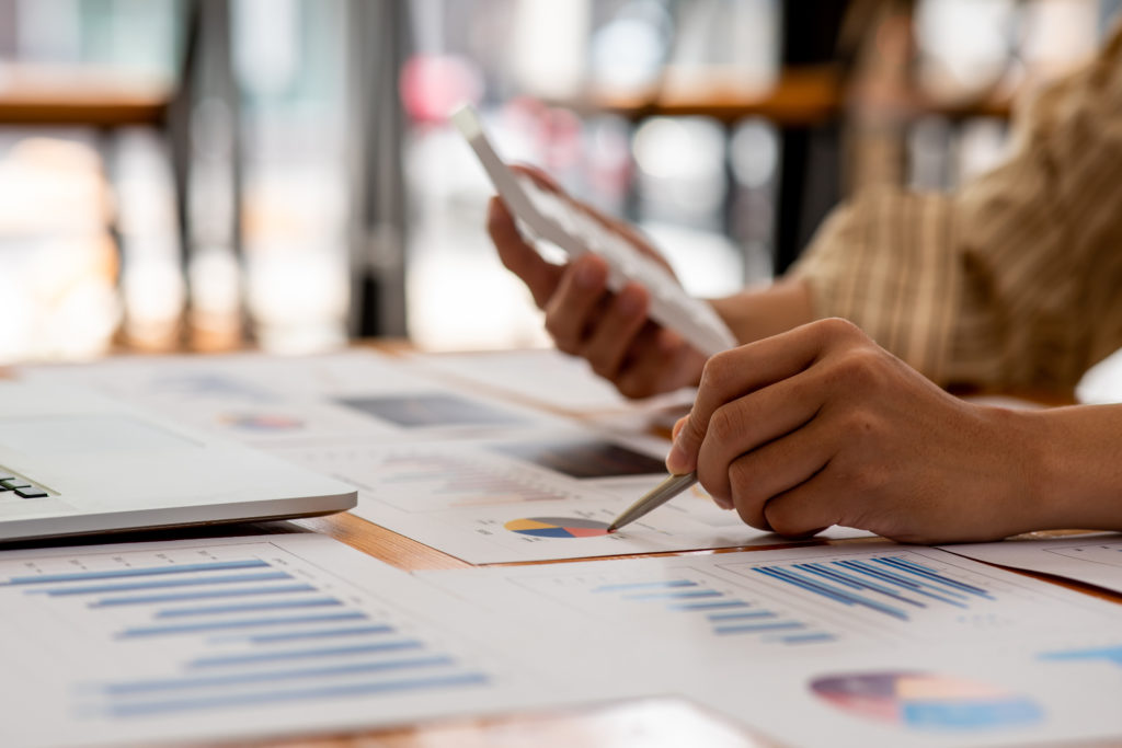 A hand holding documents featuring charts and graphs