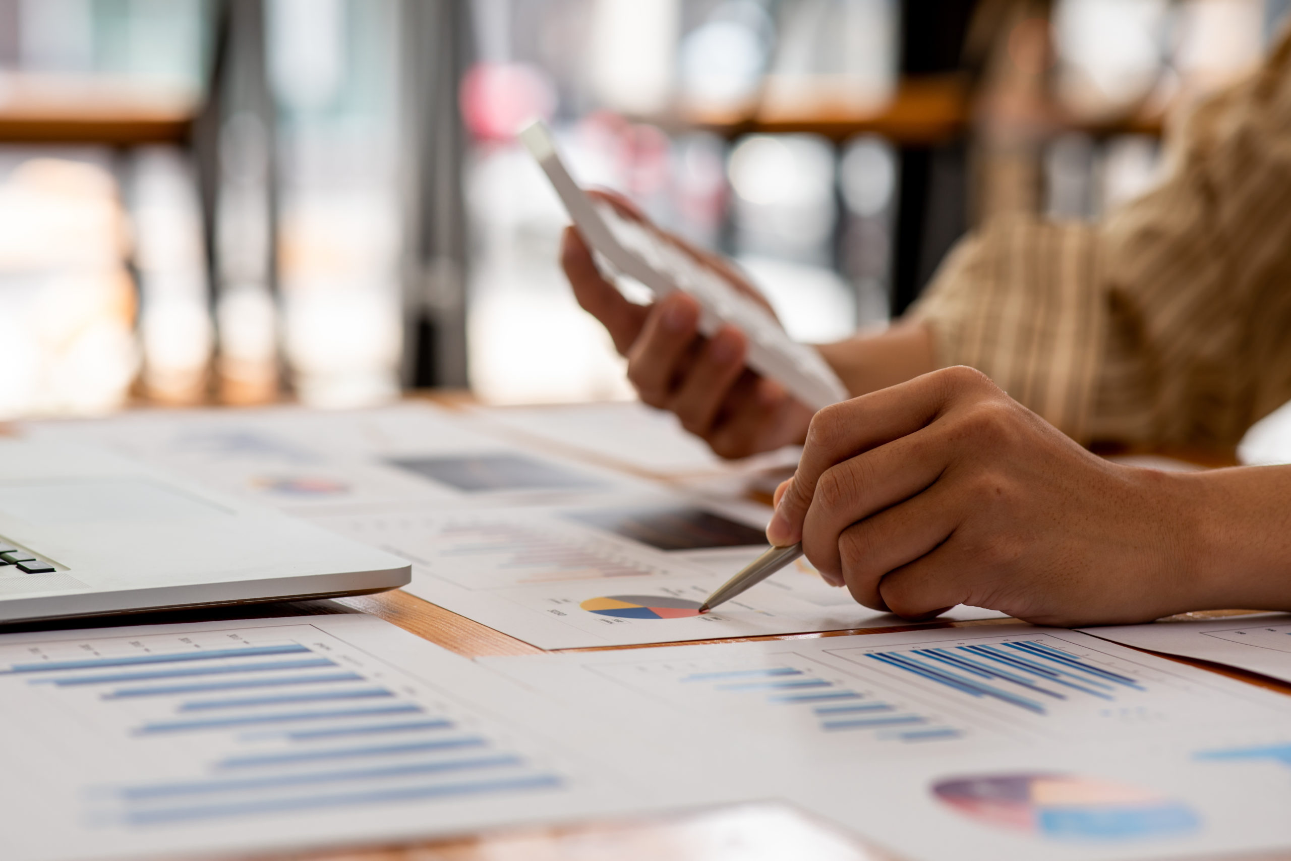 A hand holding documents featuring charts and graphs