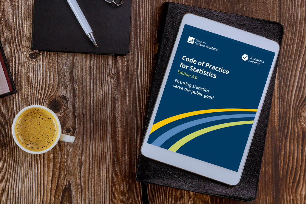 A tablet screen resting on a desk next to a cup of coffee - the tablet is displaying the Code of Practice for Statistics edition 3.0